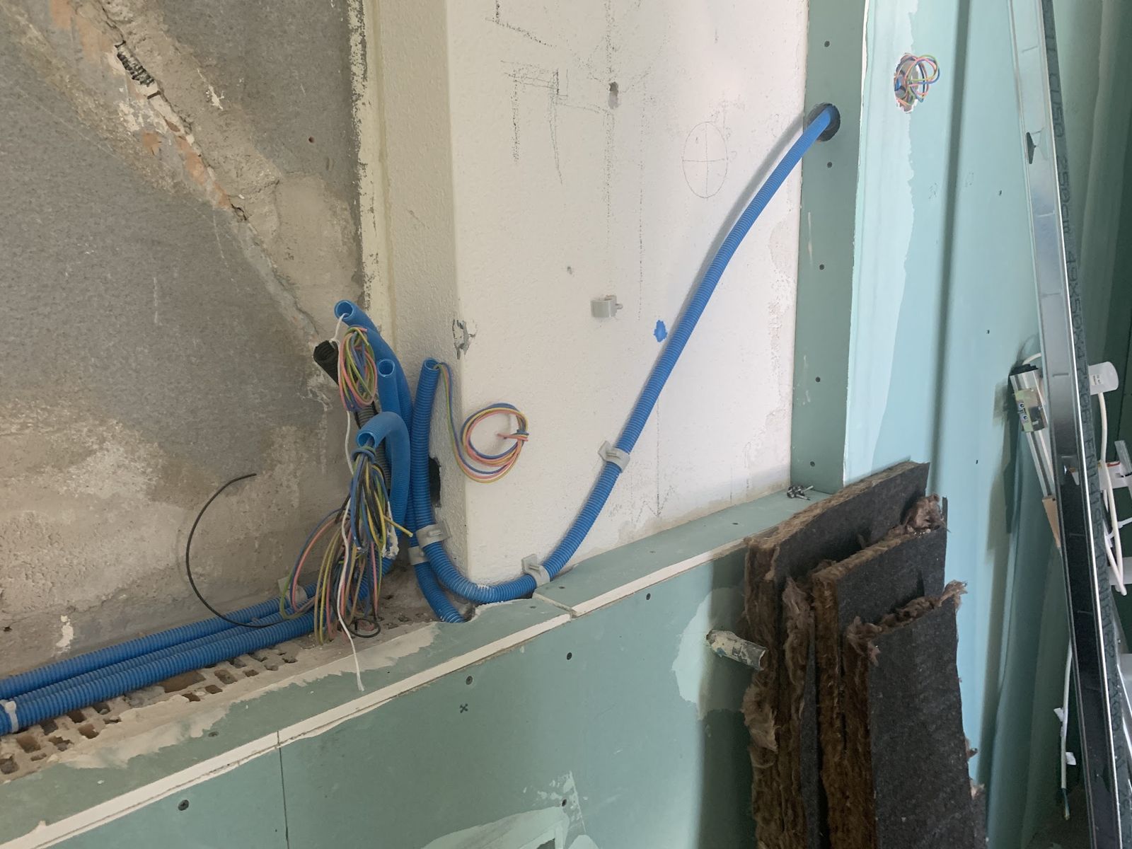 Elektroleitungen in blauen Rohren in einer geöffneten Wand