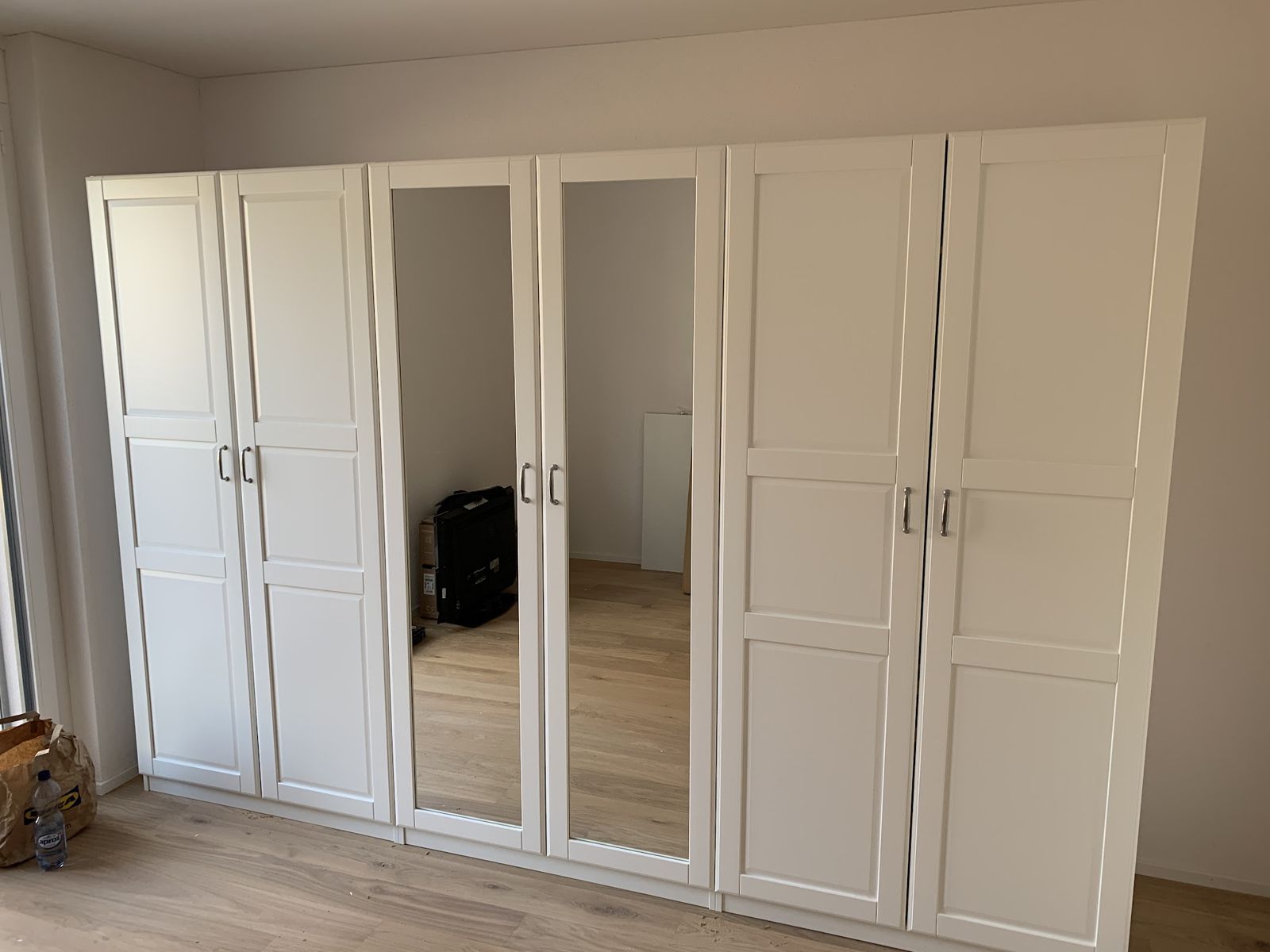Aufgebauter weisser Kleiderschrank mit Spiegeltüren