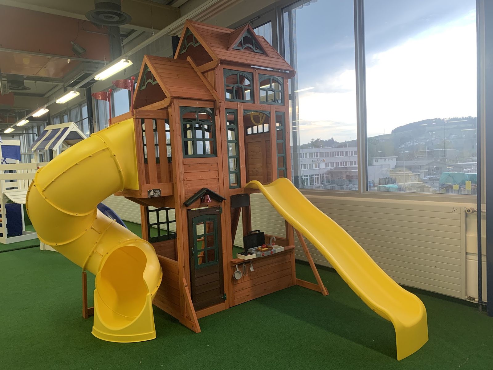 Aufgebauter Spielturm aus Holz mit gelber Rutsche in einem Innenraum